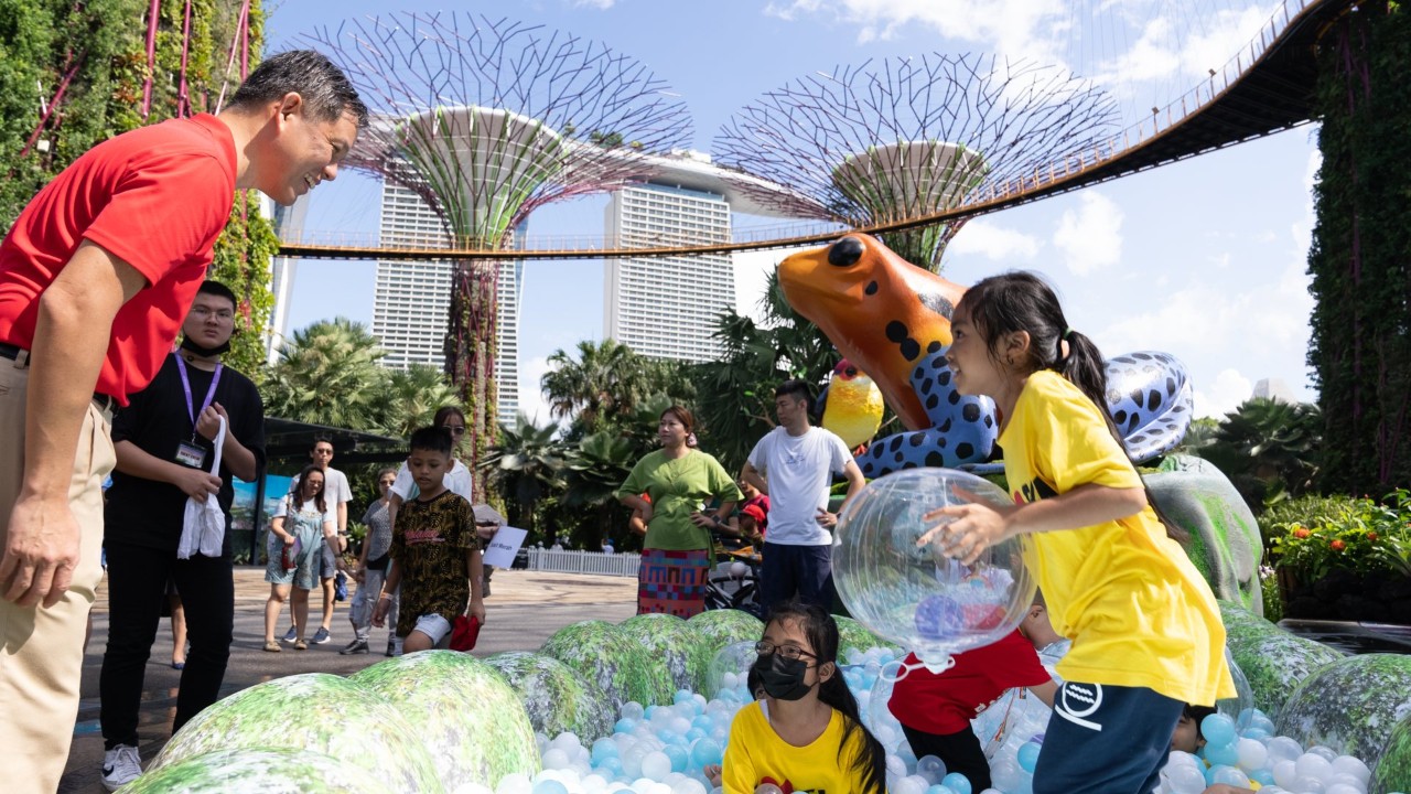 Minister for Education Chan Chun Sing watches over kids playing in a ball pit resembling frog eggs in a pond, at the poison dart frogs installation at the nature-inspired playground at Supertree Grove.