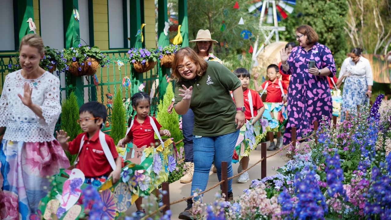 Sixteen preschool children donning floral floats they made in art class march alongside delegates from Toowoomba and horticulturists at the launch of Gardens by the Bay’s Carnival of Flowers.